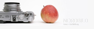 Kamera, Apfel und Wasserzeichen aus dem Firmenloge der Nordbild GmbH erstellt